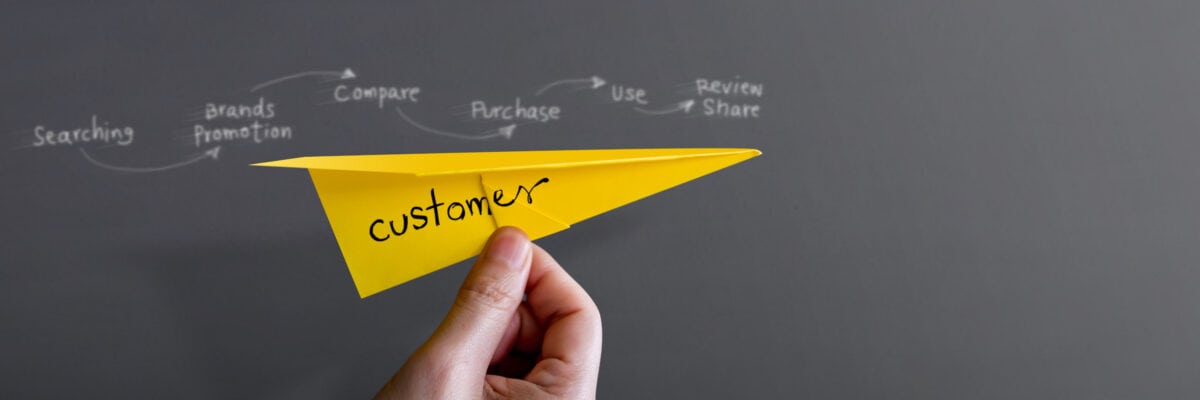 Customer Journey and Experience Concept. Hand Raise Up a Paper Plane against the Wall, Graphic and Text about Client's Journey as background. Side View